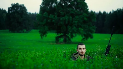 Hunter is lying in a field and prepare to shoot Stock Footage 94303729
