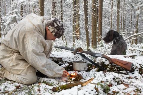 A hunter makes a fire in winter with a match Stock Photos