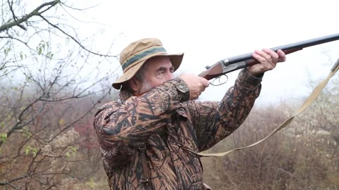 Hunter man with gray beard in hunter suit load cartridges in a double-barreled r Video stock 164292512
