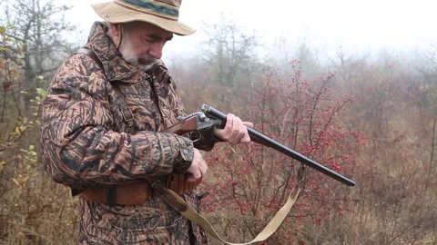 Hunter man with gray beard in hunter suit load cartridges in a double-barreled r Video stock 164292903