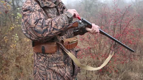 Hunter man with gray beard in hunter suit load cartridges in a double-barreled r Video stock 164292996