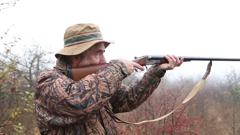 Hunter man with gray beard in hunter suit load cartridges in a double-barreled r Stock Footage 164293111