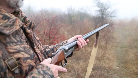 Hunter man with gray beard in hunter suit load cartridges in a double-barreled r Video stock 164293341
