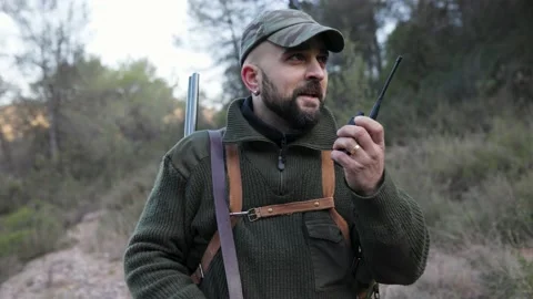 Hunter man talking to someone on a walkie-talkie outdoors in nature. Video stock 237116409