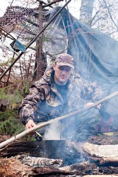 Hunter prepares food on fire Stock Photos
