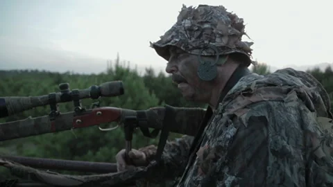Hunter preparing for big game in forest at sunset near mountain range Stock Footage 327961686