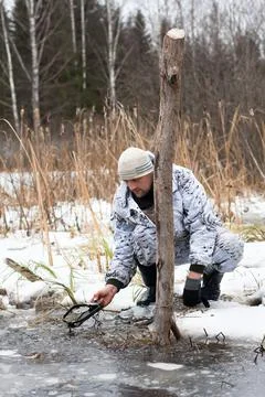 The hunter pulls the trap out of the water Stock Photos