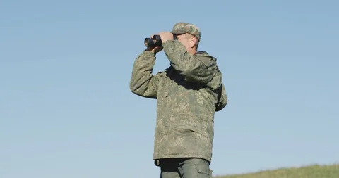 Hunter raised his binoculars, looking for his next destination in the mountains Stock Footage 128414433