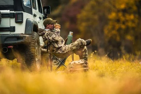 Hunter Seating Next to His All Wheel Drive Vehicle and Drinking Coffee 库存照片