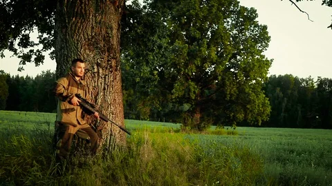 Hunter stands under a tree and tracks down prey Stock Footage 94298609