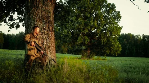 Hunter stands under a tree and tracks down prey 스톡 동영상 97701942