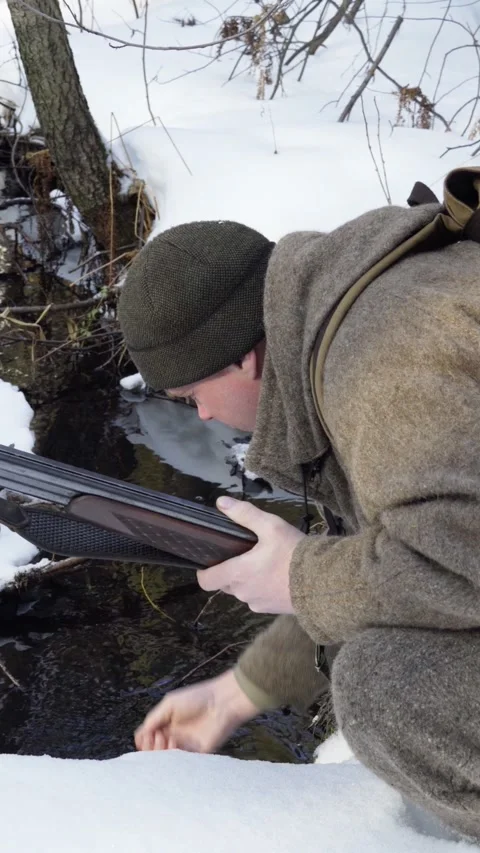The hunter stopped at a mountain stream in the winter forest to drink water. Stock Footage 317944598