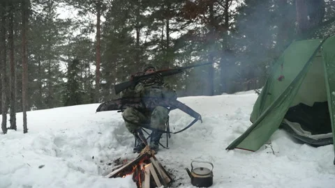 The hunter takes out a gun from the case, sitting in the winter camp by the fire Stockbeeldmateriaal 170441836