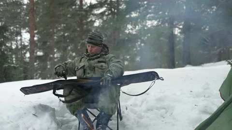 The hunter takes out a gun from the case, sitting in the winter camp by the fire Stockbeeldmateriaal 170442290