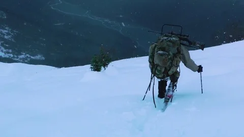 Hunter walking on mountain slope during snowfall Stock Footage 83183910