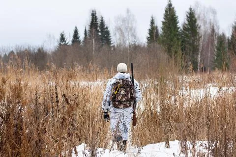 Hunter walking on the snowy field Stock Photos