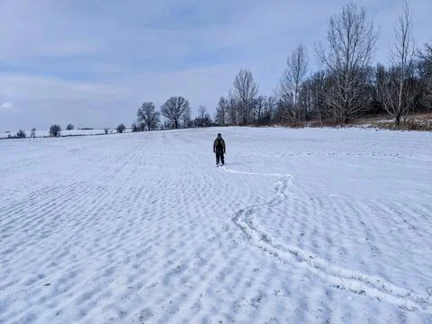 Hunter walking through a snow-covered winter agricultural field outdoors Foto stock