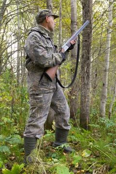 A hunter with a weapon in his hands stands in a thicket of aspen Stock Photos