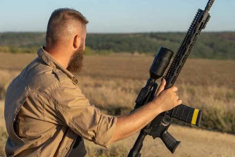 A hunter with a weapon on the hunt against the backdrop of a beautiful summer Stock Photos