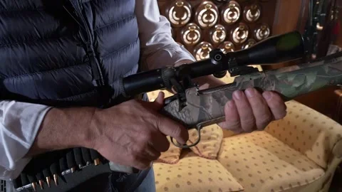 Hunter's hands loading a bolt-action rifle with ammunition in a hunting lodge Stock Footage 331182620