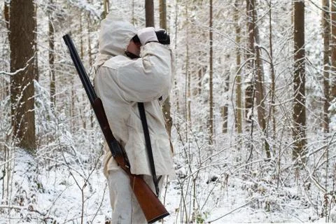 Huntsman looks through binoculars while hunting in the winter forest Stock Photos