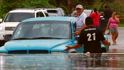 Hurricane Fiona Puerto Rico - Man Helping Senior Citizen Cross Flooded Road Stock Footage