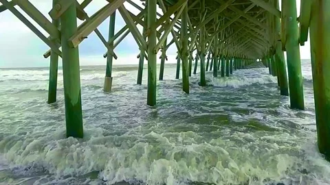 Hurricane induced waves slam pilings beneath pier Stock Footage 139935408