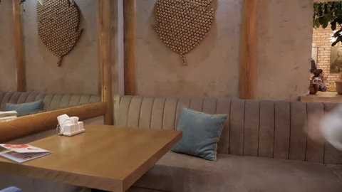 Hurrying man sits down on sofa with pillow at table in cafe Stock Footage 106327971