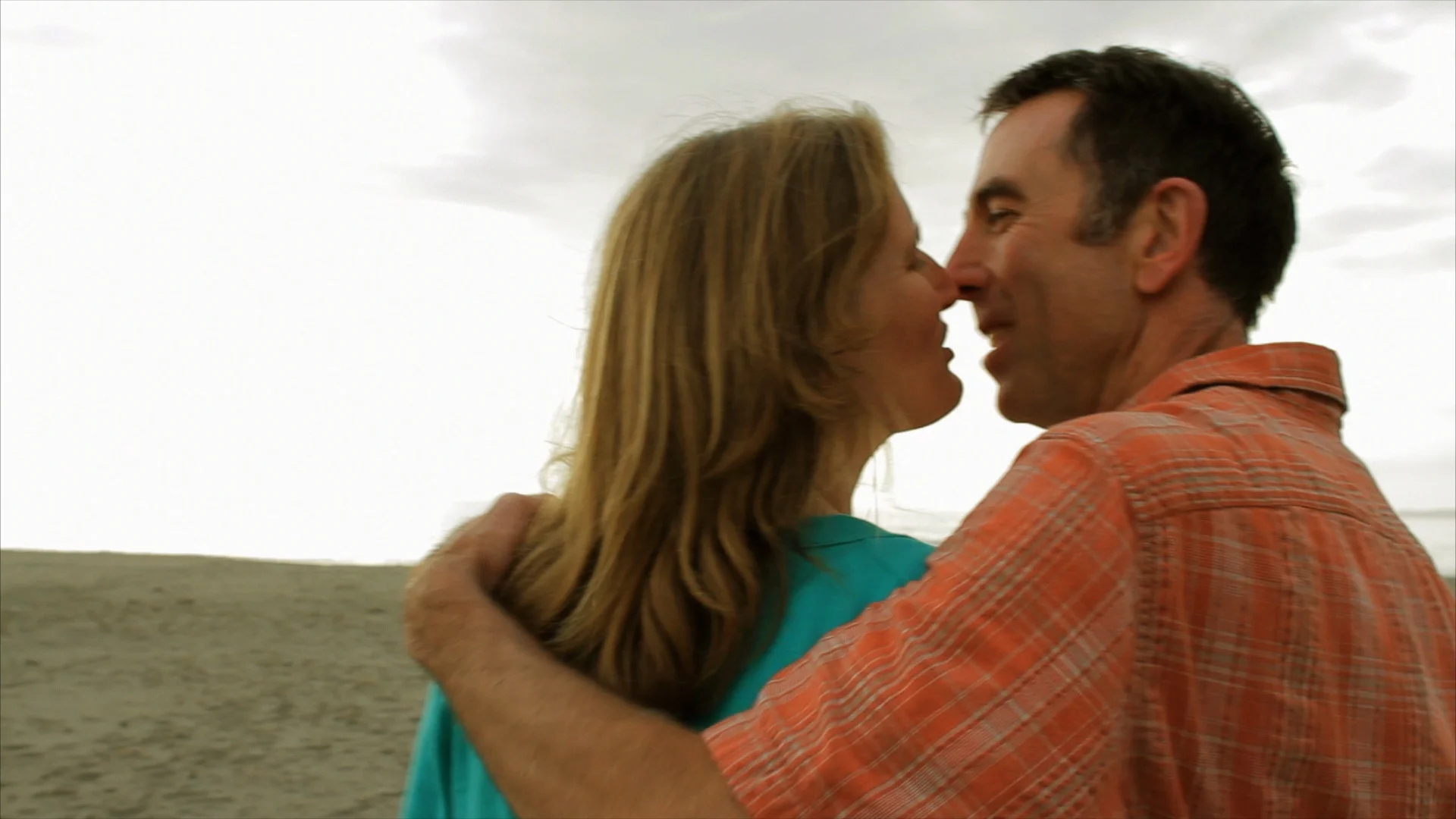 Husband and wife kissing at beach.