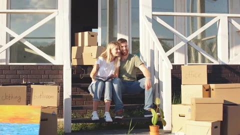 Husband and wife standing in front of new buying home with boxes Stock Footage