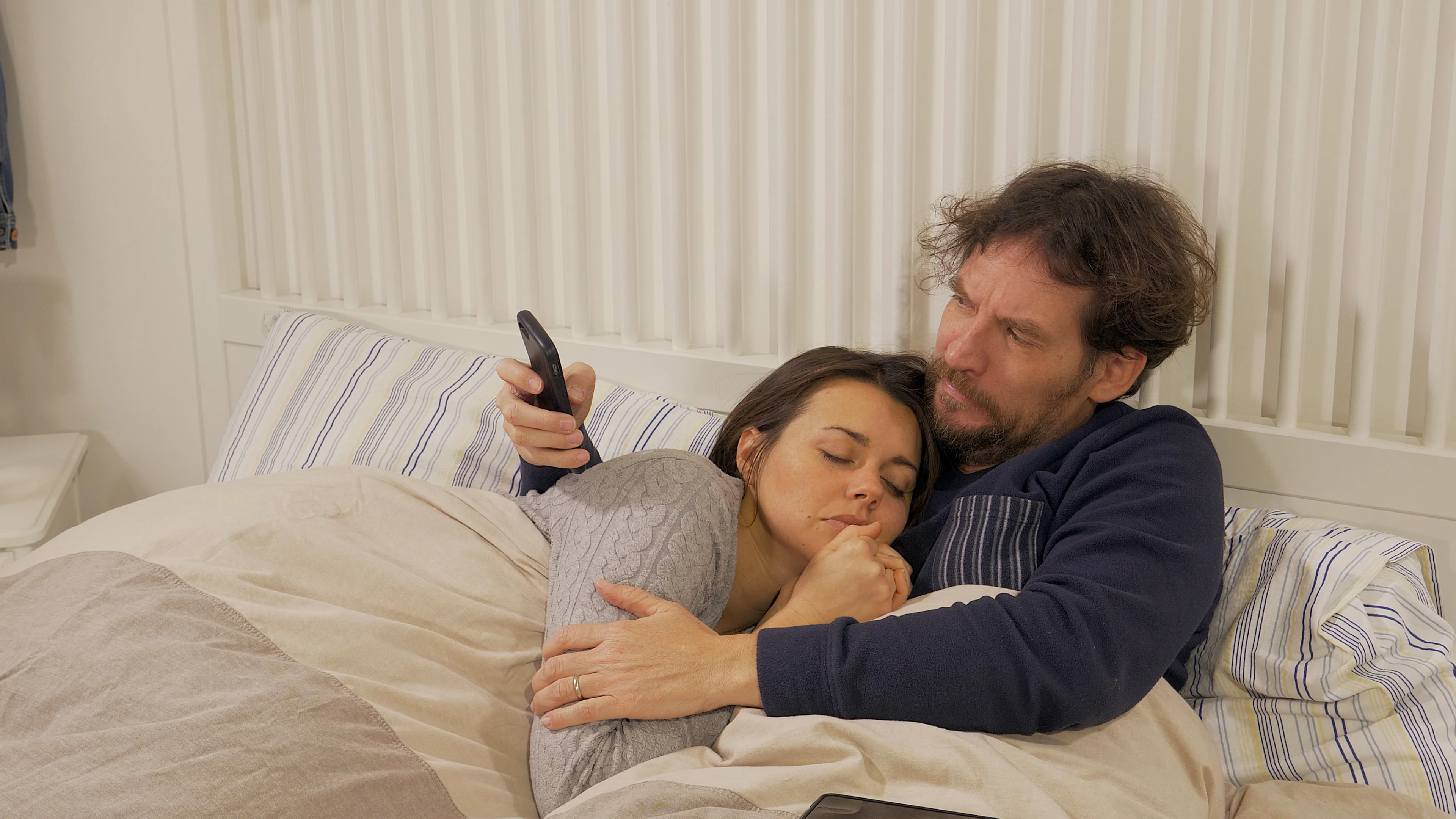 Husband cheating on sleeping wife in bed with cell phone photo