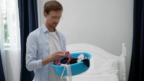 The Husband Is Doing Some Housework While Holding A Basket With Laundry In His Stock Footage 126127125