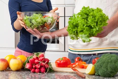 Husband helping his wife in kitchen Stock Photos