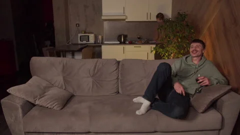 Husband with a remote control in his hands and a glass of wine watching TV Stock Footage 145085799