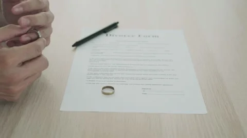Husband remove married ring between waiting sign divorce document. Concepts o Stock Footage 164664690