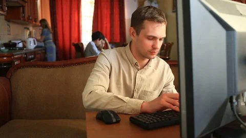 The husband sits at the computer in social networks, while his wife and children Stock Footage 75457935