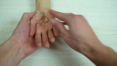 Husband's hand takes off wedding ring and puts it in wife's hand Stock Footage 235044630