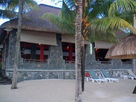 A hut on a beach with few trees in the foreground and chairs for relax Stockfoto's