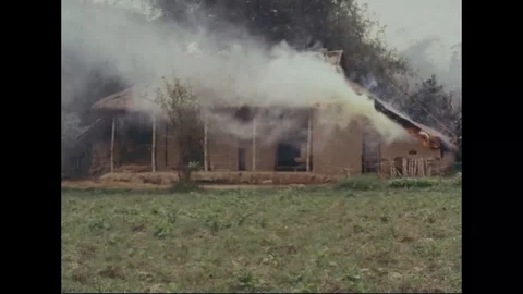 Hut burning with fire set by soldiers - 1966 Stock Footage 98244637
