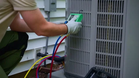 HVAC service worker diagnoses or repairs air conditioner compressor. HVAC Vidéo 314685665