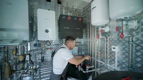 HVAC Technician Adjusting Heat Pump and Boiler System in Modern Mechanical Room Stock Footage 340112169