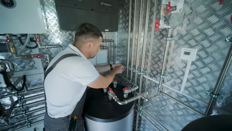 HVAC Technician Adjusting Heat Pump and Boiler System in Modern Mechanical Room Stock Footage 340112180