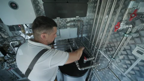 HVAC Technician Adjusting Heat Pump and Boiler System in Modern Mechanical Room Stock Footage 340112193