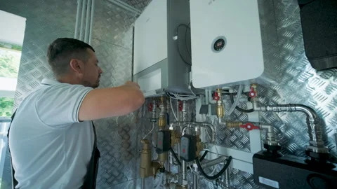 HVAC Technician Adjusting Heat Pump and Boiler System in Modern Mechanical Room Stock Footage 340112210