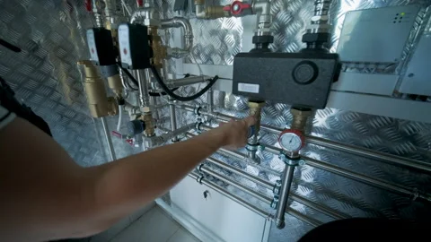 HVAC Technician Adjusting Heat Pump and Boiler System in Modern Mechanical Room Stock Footage 340112220