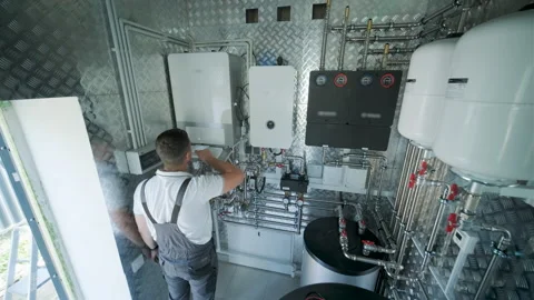 HVAC Technician Adjusting Heat Pump and Boiler System in Modern Mechanical Room Stock Footage 340112221