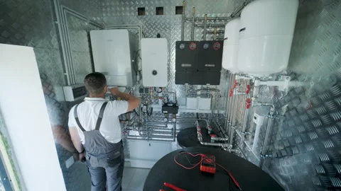 HVAC Technician Adjusting Heat Pump and Boiler System in Modern Mechanical Room Stock Footage 340112236