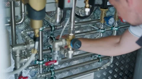 HVAC Technician Adjusting Heat Pump and Boiler System in Modern Mechanical Room Stock Footage 340112397