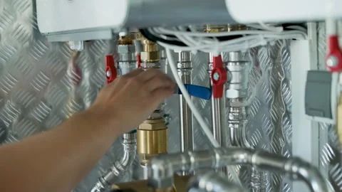 HVAC Technician Adjusting Heat Pump and Boiler System in Modern Mechanical Room Stock Footage 340112399