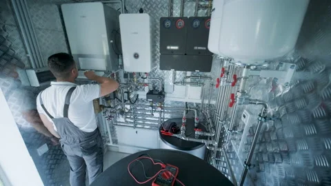 HVAC Technician Adjusting Heat Pump and Boiler System in Modern Mechanical Room Stock Footage 340112441